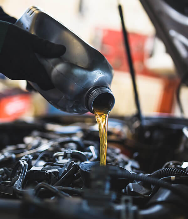 Mechanik nalieva olej do motora auta. Kontrola a výmena oleja v aute. Dôležitá údržba auta. Ako naliať olej do auta.